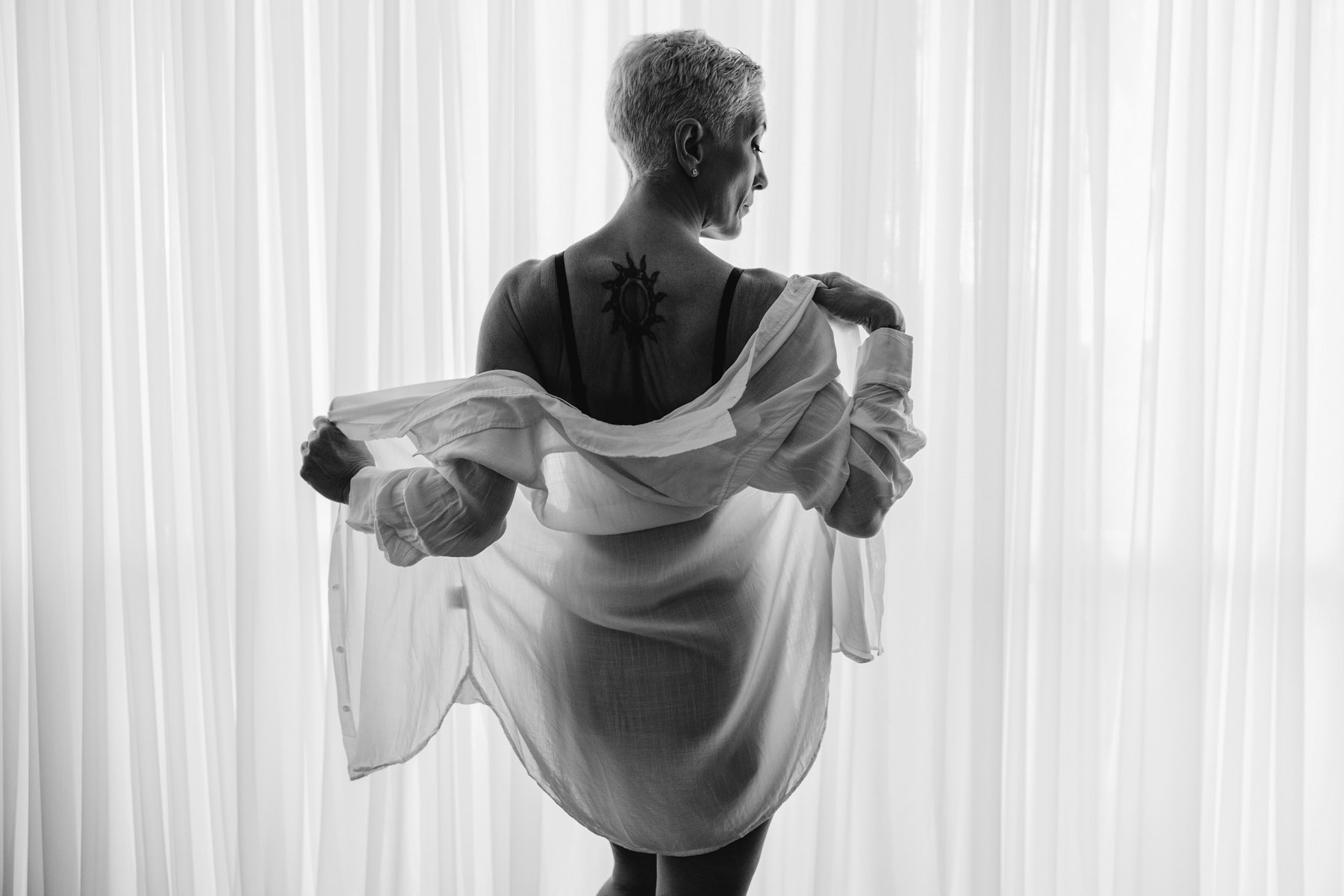 Elegant silver-haired woman backlit by studio curtains