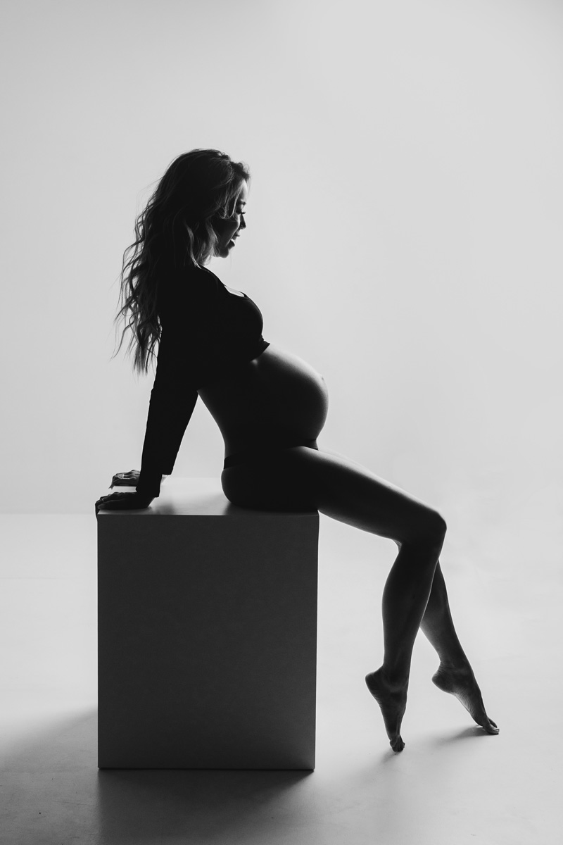 Boise modern maternity — editorial silhouette seated on a studio cube